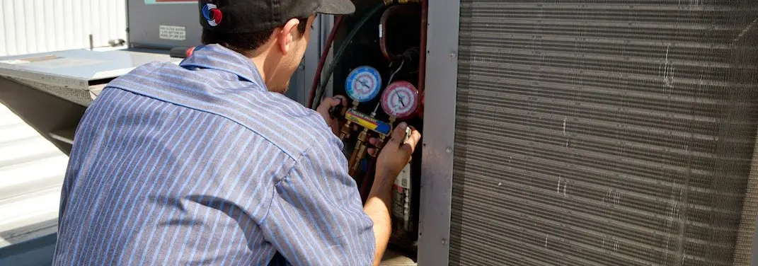 HVAC technician servicing a condenser unit in La Porte